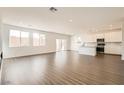 Open-concept living space with wood floors and an adjacent kitchen with white cabinets at 9881 Lost Horse Ave, Las Vegas, NV 89178