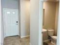 Bright entryway featuring tile flooring, a white front door, and a convenient half-bathroom at 8279 Palladium St, Las Vegas, NV 89113