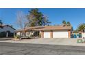 Ranch-style home with a three-car garage and mature landscaping at 3544 Sandcliff Ln, Las Vegas, NV 89121