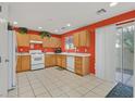 Well-lit kitchen with wood cabinets, tiled floor, white appliances, and a sliding glass door to the backyard at 6058 Ambleshire Ave, Las Vegas, NV 89139