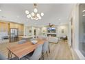 Open concept dining room with a long wooden table and modern light fixture at 4660 Fiore Bella Blvd, Las Vegas, NV 89135