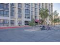 View of the apartment building entrance with palm trees and parking for bikes and scooters at 3930 University Center Dr # 1003, Las Vegas, NV 89119