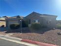 Tan one-story house with a tile roof, two-car garage, and landscaped yard at 5521 Little Lake Ave, Las Vegas, NV 89122