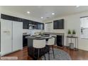 Well-lit kitchen features modern black cabinets and an island with white bar stools at 6485 Arrow Cottage Ct, Las Vegas, NV 89130