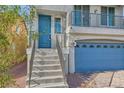 Front view of a two-story house with gray siding and a blue door at 7745 Tyrell Peaks St, Las Vegas, NV 89139