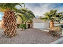 Tan house with a white garage door and palm trees at 1565 Pasture Ln, Las Vegas, NV 89110