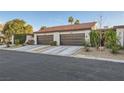 Attached two-car garage with brown doors, tile roof, and desert landscaping at 3143 Sonata Dr, Las Vegas, NV 89121