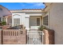 Inviting front entry with a gated patio, brick wall, and mature shrubs at 5683 Whale Watch St, Las Vegas, NV 89113