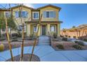 Tan townhome with gray shutters, landscaping, and walkway at 965 Nevada State Dr # 1101, Henderson, NV 89002