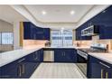 Modern kitchen featuring sleek blue cabinets, stainless steel appliances, and bright countertops at 2240 Mohigan Way, Las Vegas, NV 89169