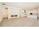 Open-concept living space with modern fireplace and gourmet kitchen with white cabinetry at 106 Barkset Way, Henderson, NV 89011
