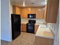 Galley kitchen with wood cabinets, black appliances, and tile floor at 3367 Villa Fiori Ave, Las Vegas, NV 89141