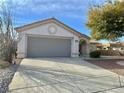 Neutral stucco single story with two car garage featuring a concrete driveway and low maintenance desert landscaping at 11037 Hawk Valley Ave, Las Vegas, NV 89134