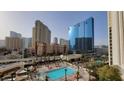 Day view of a pool surrounded by palm trees, in front of glowing Las Vegas hotels at 135 E Harmon Ave # 407, Las Vegas, NV 89109