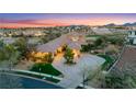 Beautiful elevated home with circular driveway, mature trees, green landscaping, and a view of the mountains at 2870 Quartz Canyon Dr, Henderson, NV 89052