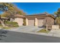 Tan house with solar panels, two-car garage, and neatly landscaped yard at 120 Emerald Dunes Cir, Henderson, NV 89052