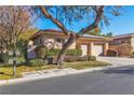 Two-story house with solar panels, two-car garage, mature tree, and lush landscaping at 120 Emerald Dunes Cir, Henderson, NV 89052