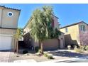 Two-story home shows a two-car garage, xeriscaping, and is situated between other similar homes on a sunny day at 11467 Monte Isola St, Las Vegas, NV 89141