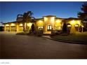 Stunning exterior view of home with multiple garage bays, beautiful landscaping, and impressive architectural details at dusk at 2111 Bogart Ct, Las Vegas, NV 89117