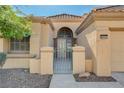 Front entry of the home with decorative gate and arched entryway at 8805 Litchfield Ave, Las Vegas, NV 89134