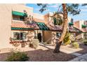 Tan stucco townhouse with green accents and mature tree in front at 6750 Del Rey Ave # 122, Las Vegas, NV 89146