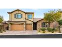 Two-story house with tan siding, brown garage doors, and stone accents at 7563 Saguaro Cactus Ave, Las Vegas, NV 89178