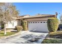 Tan house with a white garage door and neatly trimmed bushes at 9272 Cantana St, Las Vegas, NV 89123