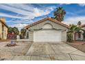 Charming single-story home featuring a two-car garage, desert landscaping, and a tile roof at 2668 Alwoodley Cir, Las Vegas, NV 89142