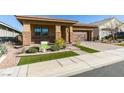 Tan house with a brown garage door and well-manicured lawn at 752 Drammatico Pl, Henderson, NV 89011