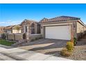 Tan colored house with a large garage and well-manicured lawn at 10499 Skye Paseo Ave, Las Vegas, NV 89166