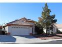 Single-story house with a two-car garage and mature tree in front at 1235 Pagentry Dr, North Las Vegas, NV 89031