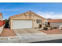 Tan stucco house featuring a white garage door and nicely landscaped front yard at 408 Matecumbe Way, Boulder City, NV 89005