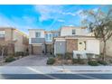 Two-story home with gray and stone accents, two-car garage, and landscaped front yard at 8595 Old Daylily Ln, Las Vegas, NV 89113