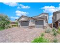 Two-story house with gray exterior, paver driveway, and landscaping at 1606 Dire Wolf Ave, North Las Vegas, NV 89084