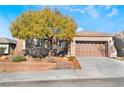 Single-story house with a brown garage door and a tree in the front yard at 2568 Dirleton Pl, Henderson, NV 89044