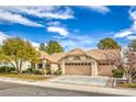 Tan house with tile roof, two car garage, and mature landscaping at 3128 Pelican Beach Dr, Las Vegas, NV 89117