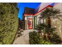 Modern home entrance featuring a vibrant red door, palm trees and verdant hedges for added privacy at 371 Tranquil Peak Ct, Henderson, NV 89012