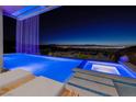 Stunning infinity pool with waterfall and city views at dusk at 665 Overlook Rim Dr, Henderson, NV 89012