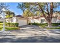 Single story home with a white garage door and mature trees at 6908 Emerald Springs Ln, Las Vegas, NV 89113