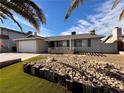 Single story home with a white garage door and rock landscaping at 730 Brick Dr, Henderson, NV 89002