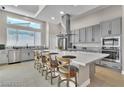Modern kitchen featuring stainless steel appliances, gray cabinets, a large island with seating, and a bright window at 10301 Fairview Ridge Ct, Las Vegas, NV 89166