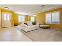 Bright living room with tiled floors, white sofas, and yellow walls at 9904 Garamound Ave, Las Vegas, NV 89117