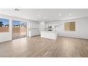 Bright living room with white walls and wood floors, seamlessly connected to an open kitchen and a sliding glass door at 334 Taylor St, Henderson, NV 89015