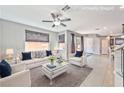 Bright, staged living room with neutral walls, tile floors, modern ceiling fan and backyard access at 2694 Marvel Astoria St, Henderson, NV 89044