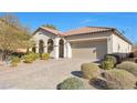 One-story home with tan colored exterior, tile roof, and landscaped front yard at 7148 Stanley Frederick St, Las Vegas, NV 89166