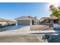 Beige house with gray garage door and landscaping at 7437 Lattimore Dr, Las Vegas, NV 89128