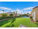 Expansive grassy backyard with mature plants and a view of the pool at 7511 Bridlehorne Ave, Las Vegas, NV 89131