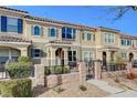 Tan two-story townhome with gray door and small front patio with seating at 2077 Via Firenze, Henderson, NV 89044