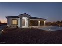 Night view of single-story home with three-car garage and landscaping at 2560 Tahachapi Ave, Pahrump, NV 89048