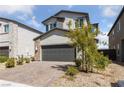 Two-story house with gray exterior, dark garage door, and landscaped front yard at 2720 High Echelon Rd, North Las Vegas, NV 89086